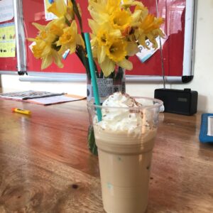 ice coffee in front of a bunch of daffodils