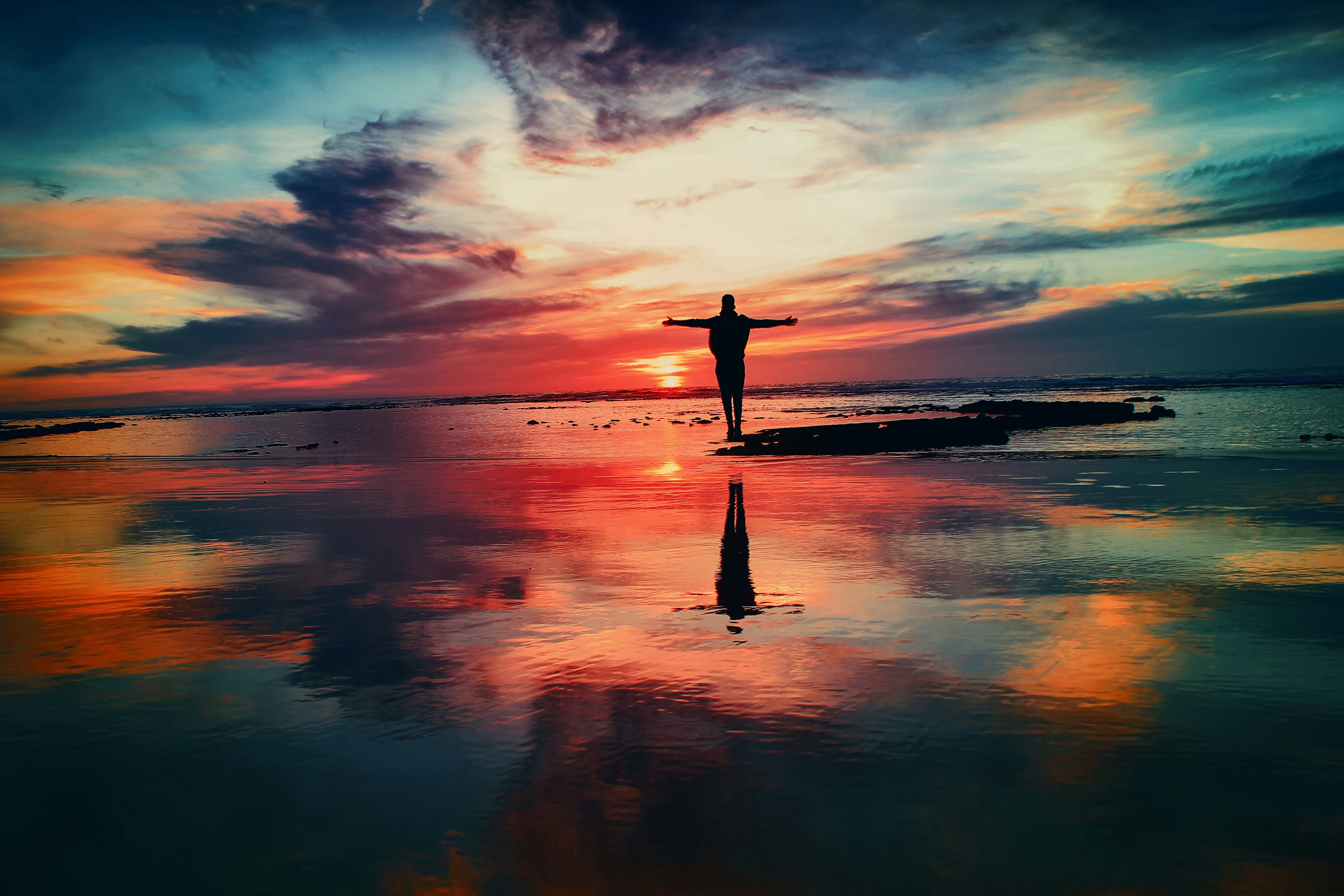 Person healing on beach during sunset