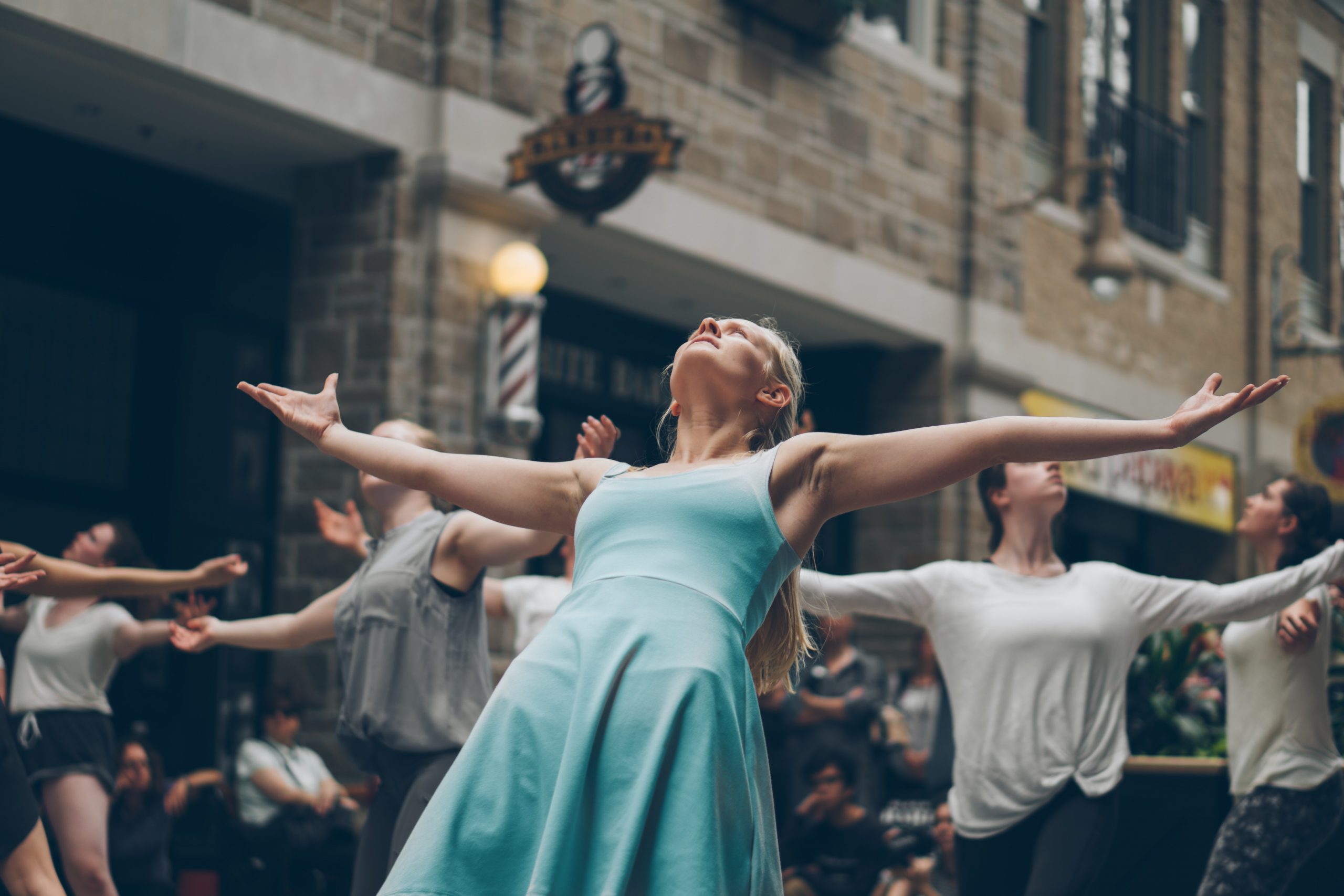 woman in blue dress with arms outstretched looking towards the sky