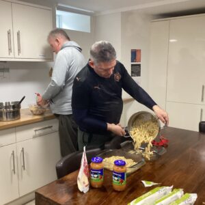 resident pouring pasta from pan into dish