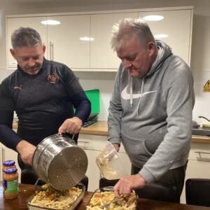 2 male residents preparing pasta dish