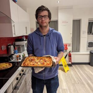 Male resident holding homemade pizza