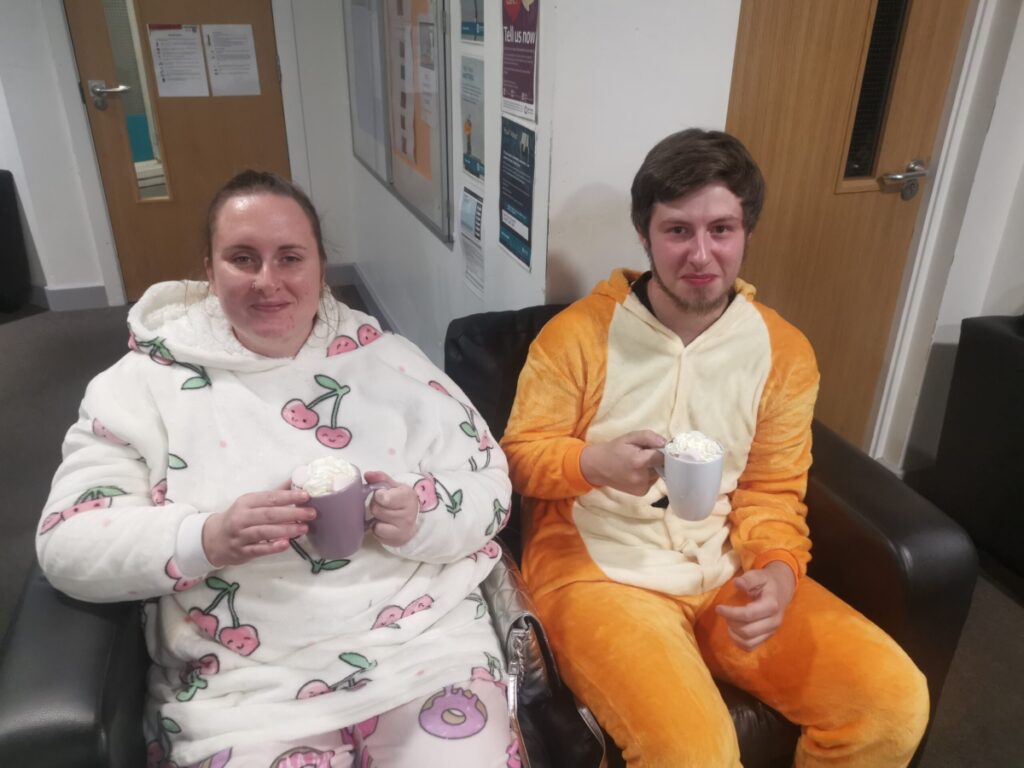 female and male residents sitting on couch in pjs holding mugs of hot chocolate