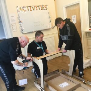 Residents and team members building pool table