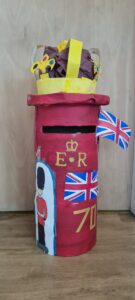 postbox decorated with crown, union jack flags and painting of soldier