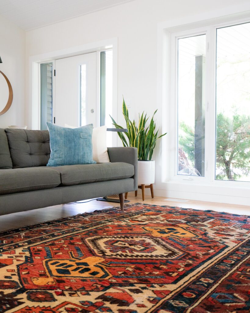 room with grey couch on orange patterned rug