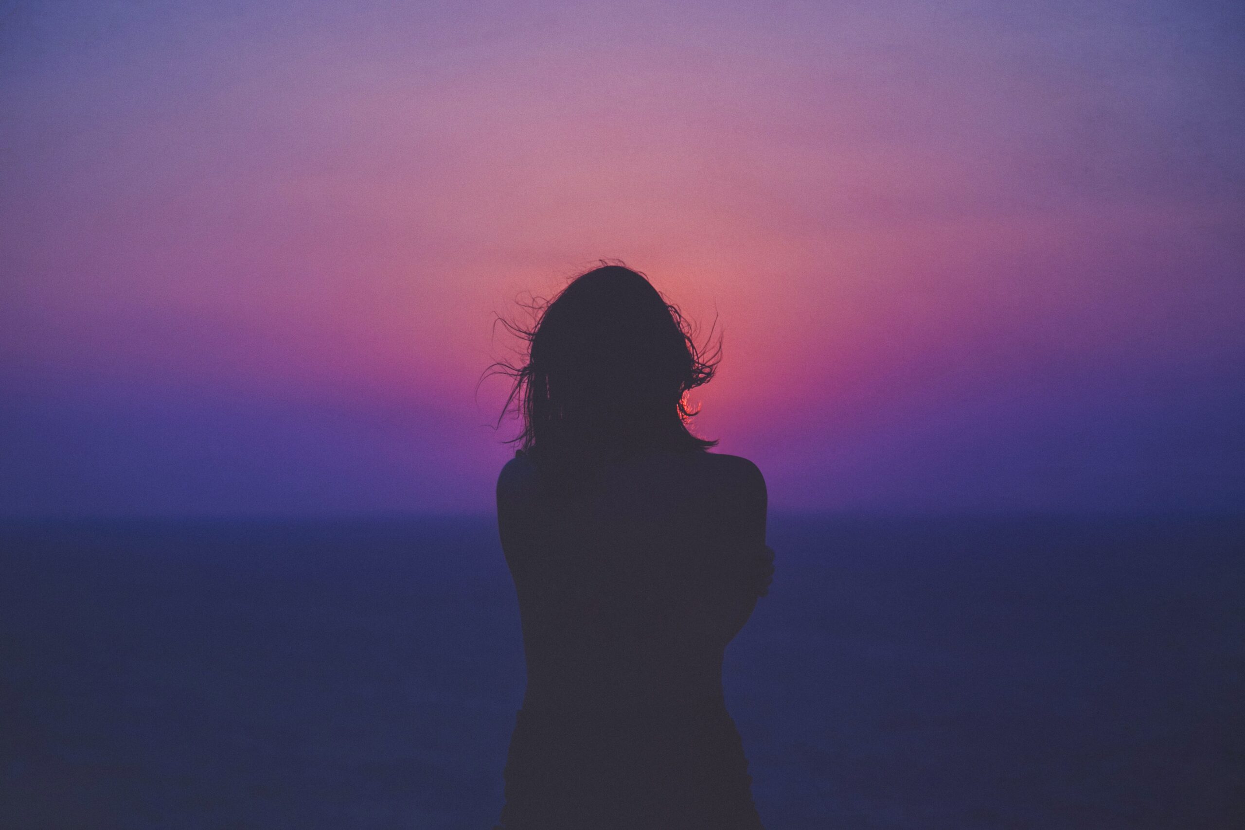 silhouette of a woman against an orange-purple background