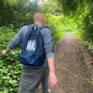 male wearing backpack walking through woodland