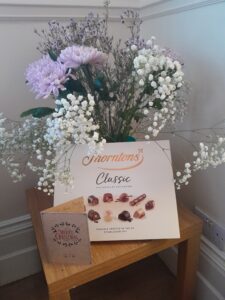 thank you card, box of chocolates and bunch of flowers on table