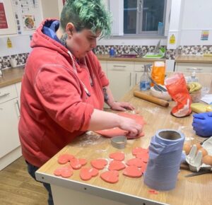 Resident making heart-shaped red cookies