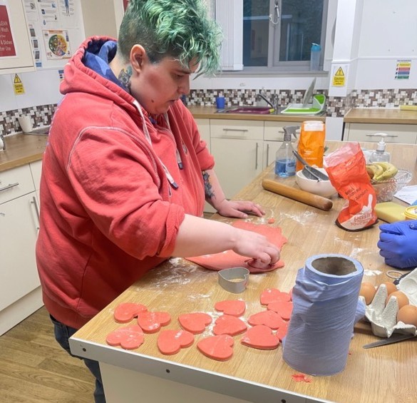 Resident making heart-shaped red cookies