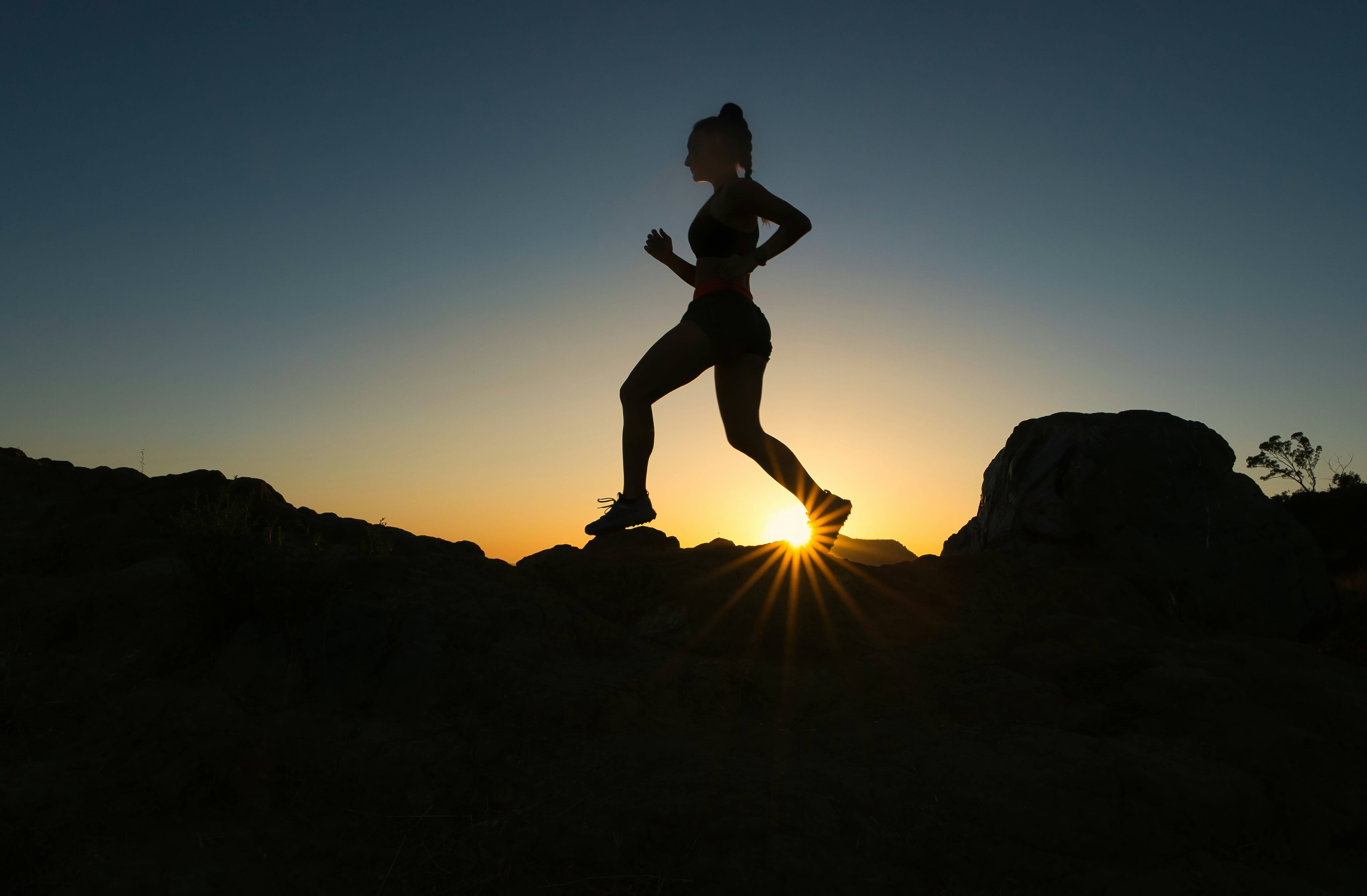 Person running over terrain at dusk to represent a blog on mental health vs mental fitness and the difference.