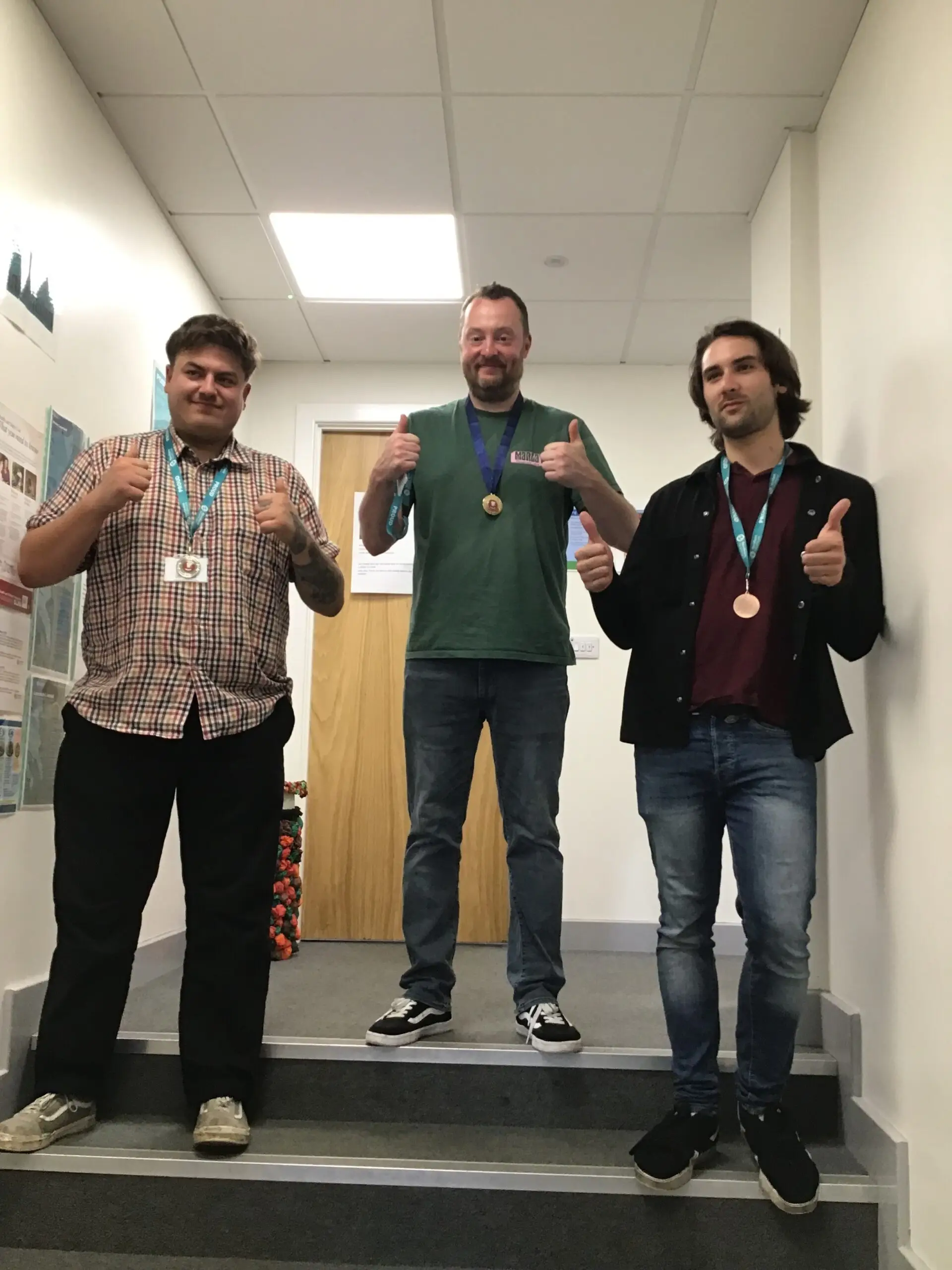 3 team members with thumbs up wearing medals