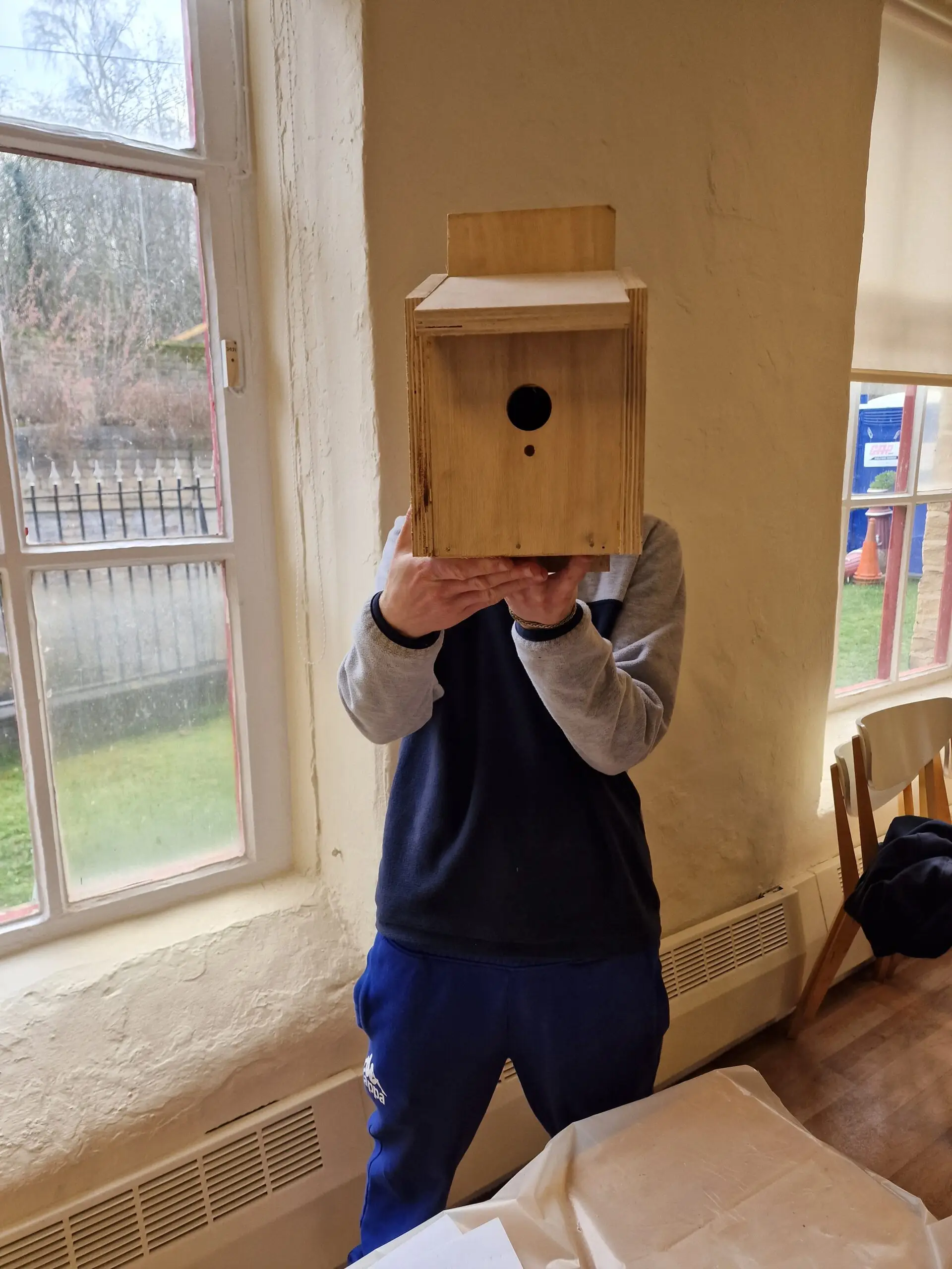 male holding wooden bird box