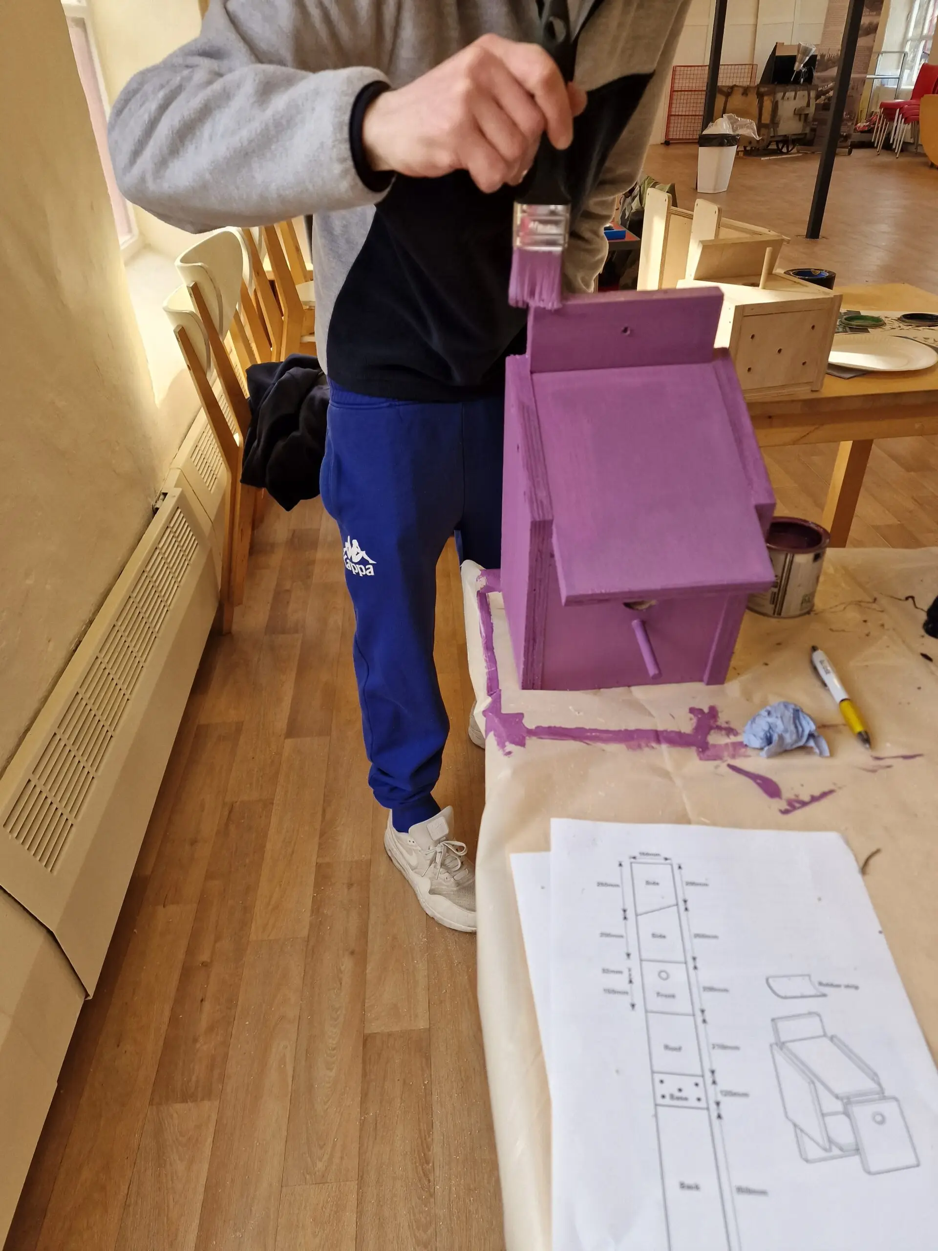 adding the finishing touches of purple paint to the bird box