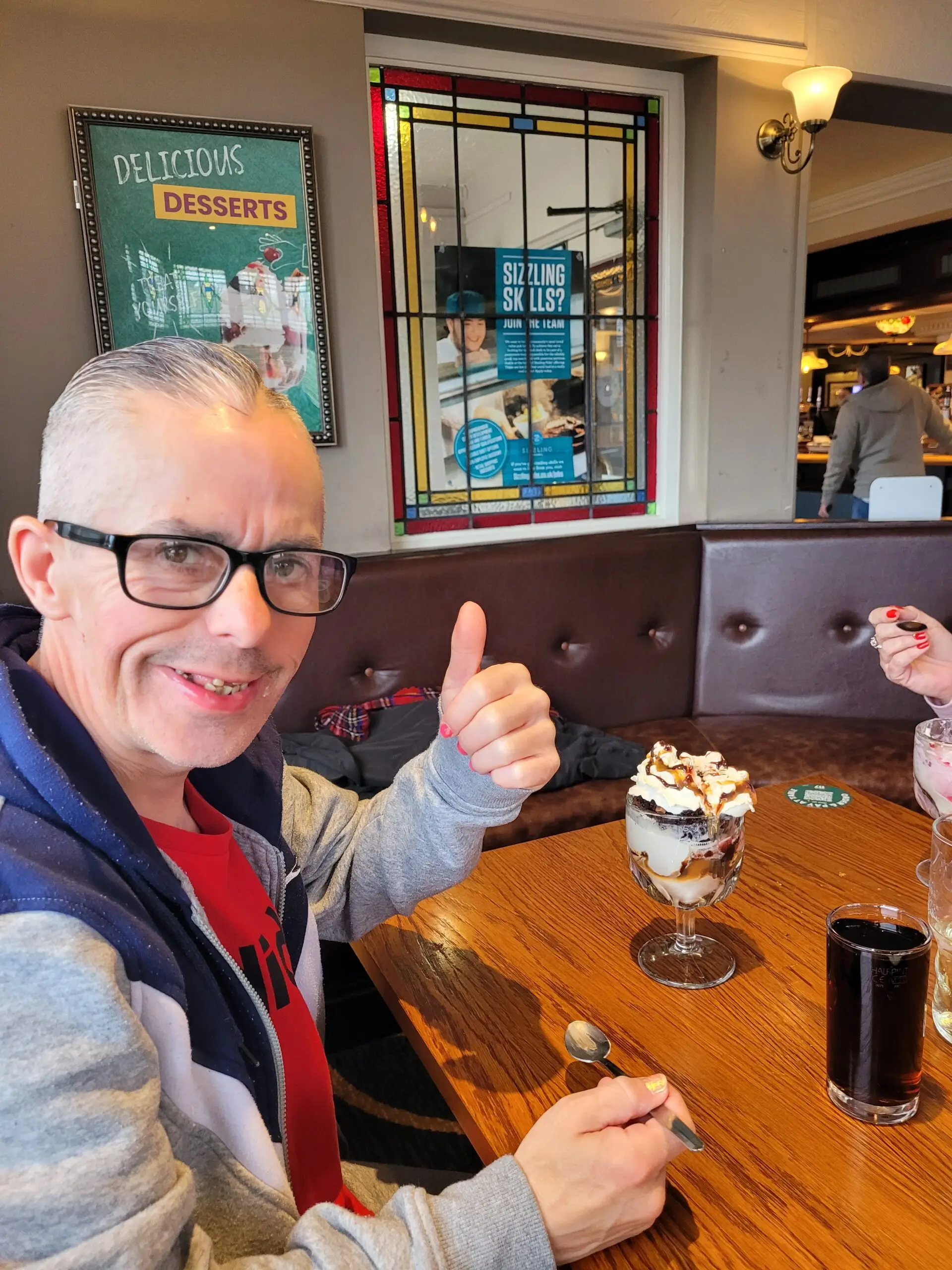 male with thumb up and ice cream sundae on table