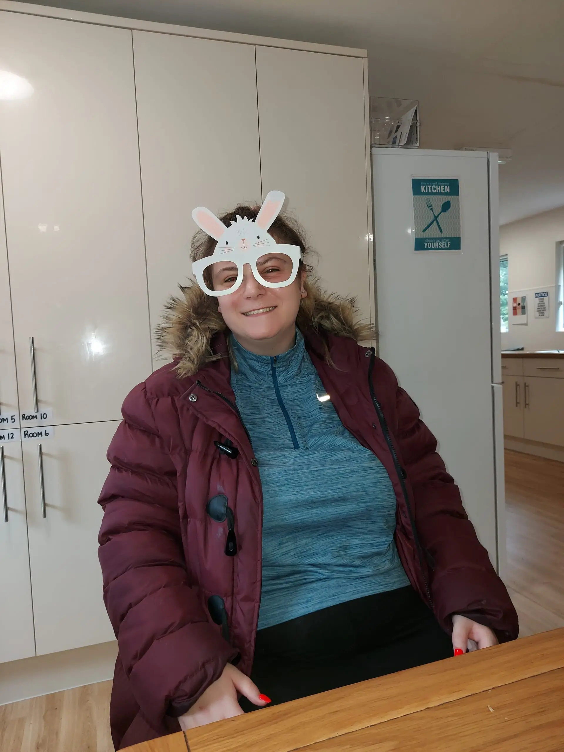 female in blue tshirt and maroon jacket wearing easter glasses