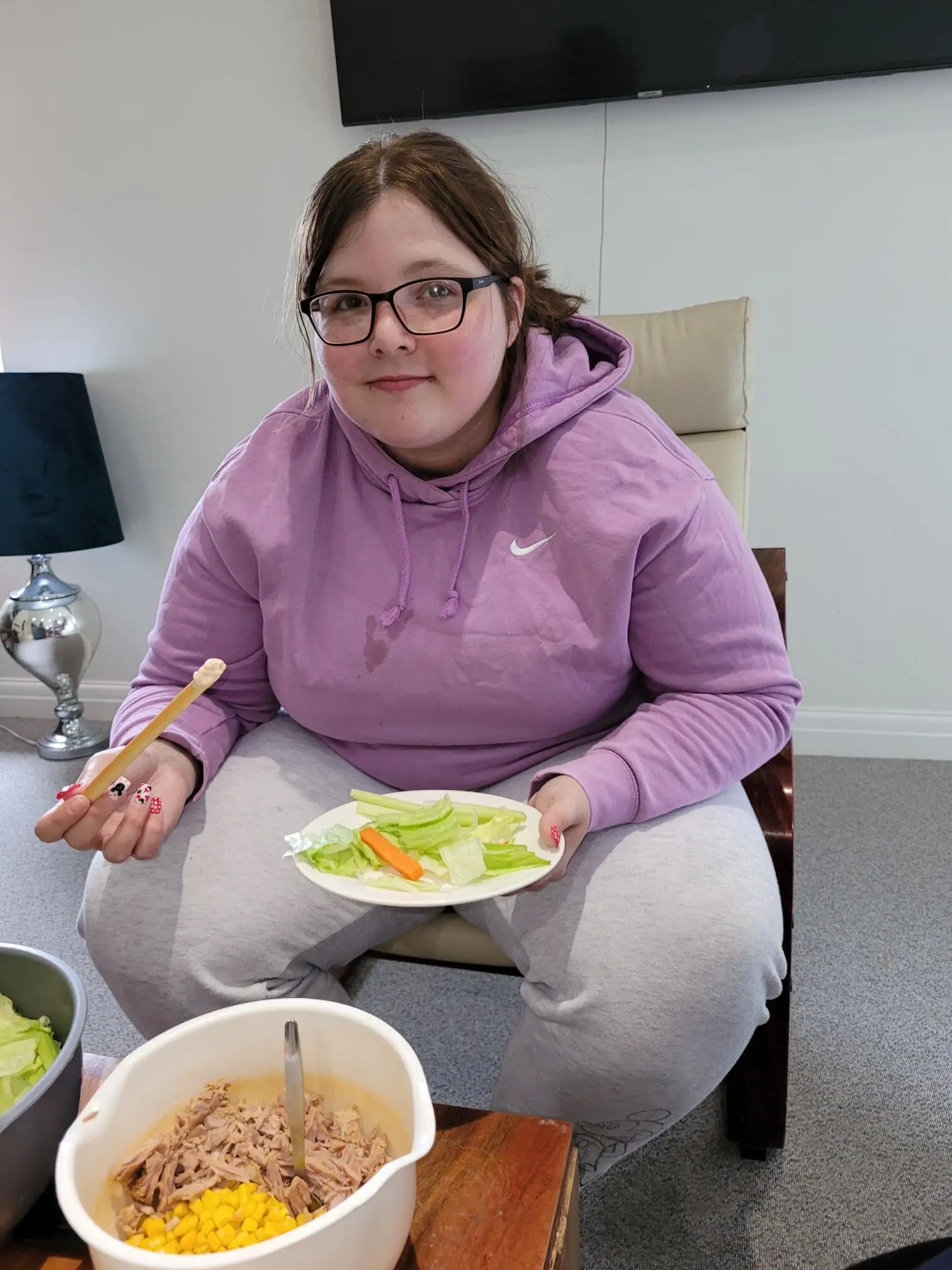 female in purple jumper holding plate of salad