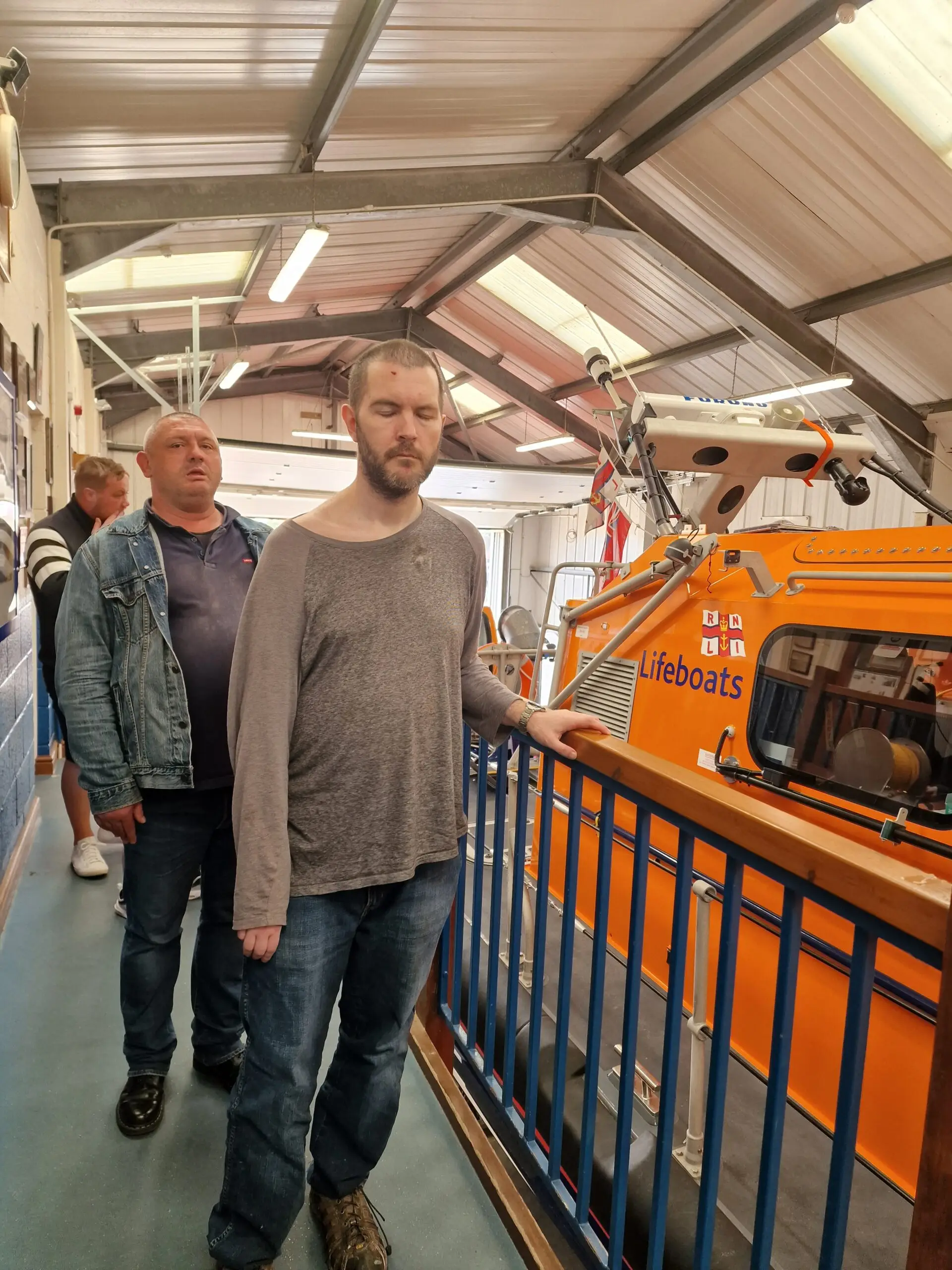 two male residents next to orange lifeboat