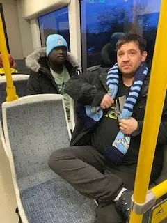 residents on the bus wearing Man City hats and scarves