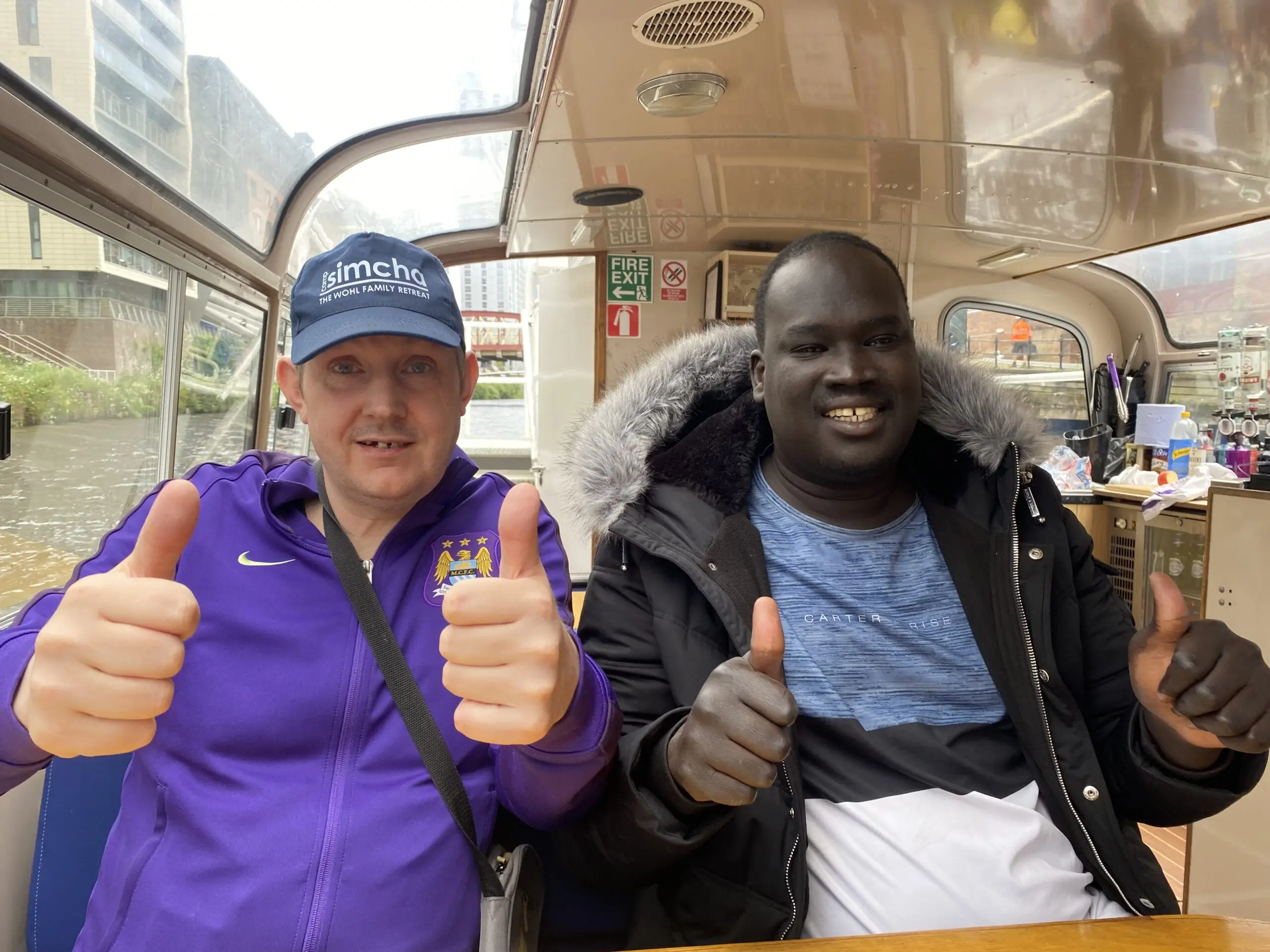 Two residents giving thumbs up on a boat