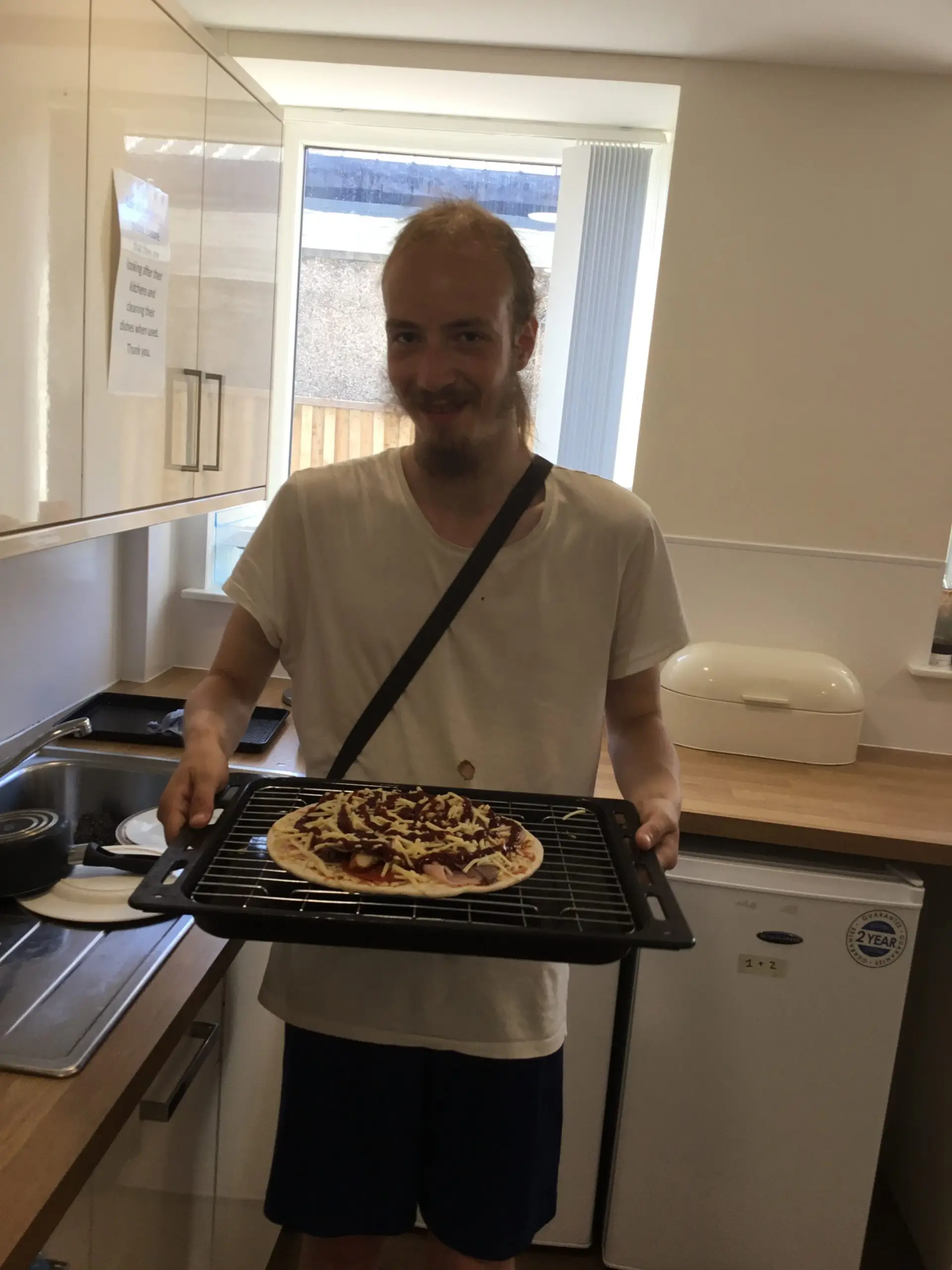 resident holding pizza ready for the oven