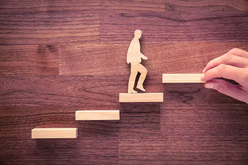 wooden depiction of man walking up stairs