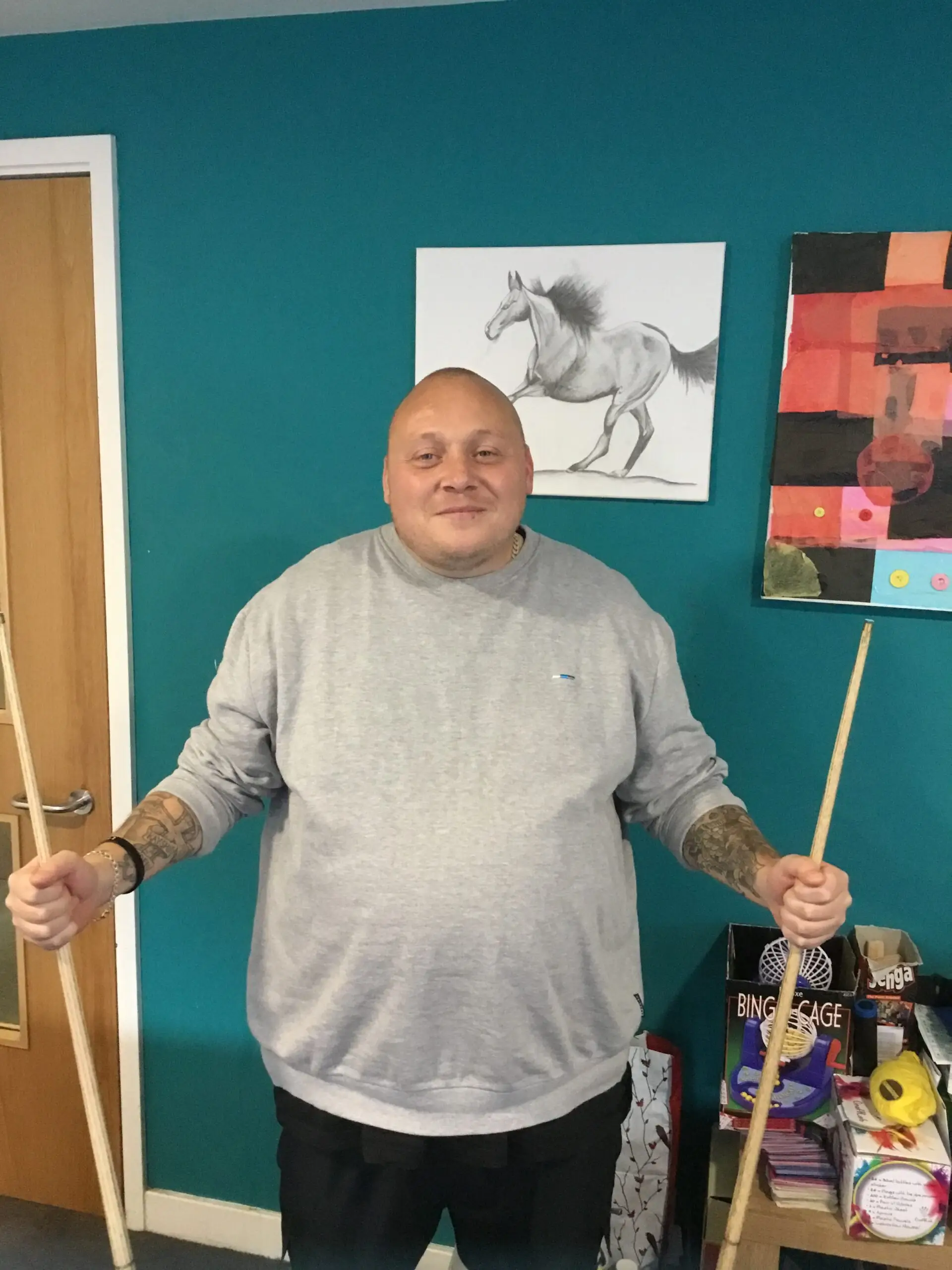 resident holding pool cues in each hand