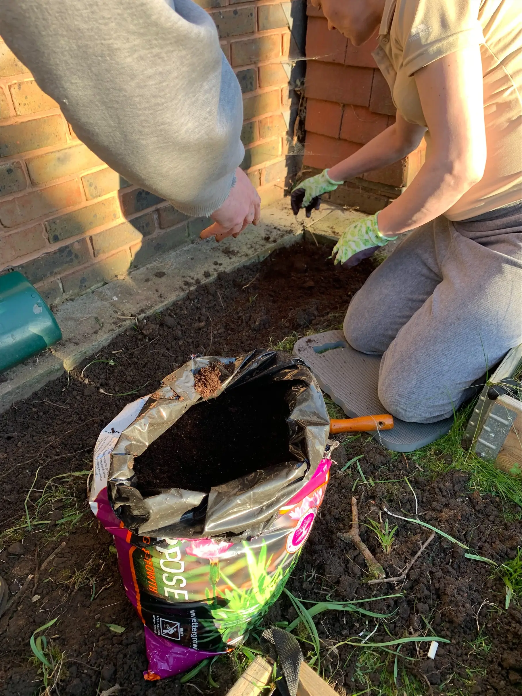 residents adding soil to flowerbed from bag of soil
