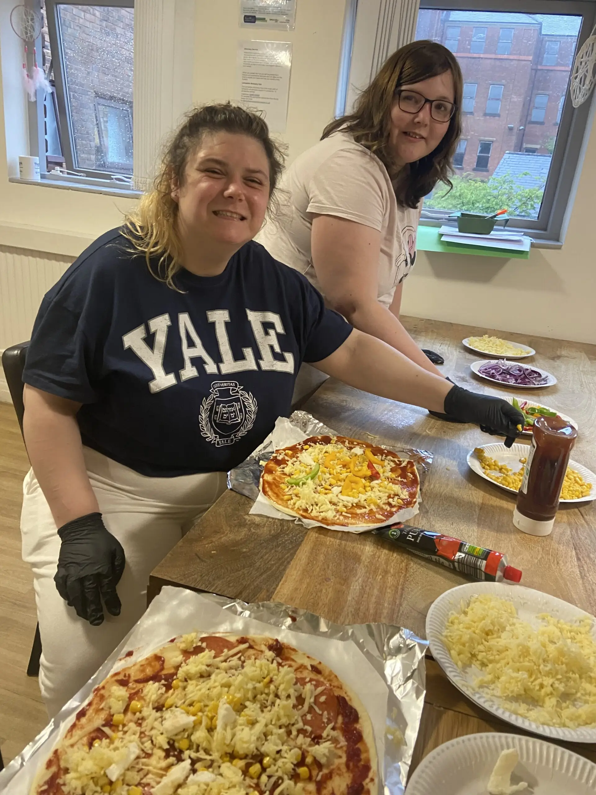 two females making homemade pizzas
