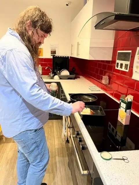 Male resident making lasagne