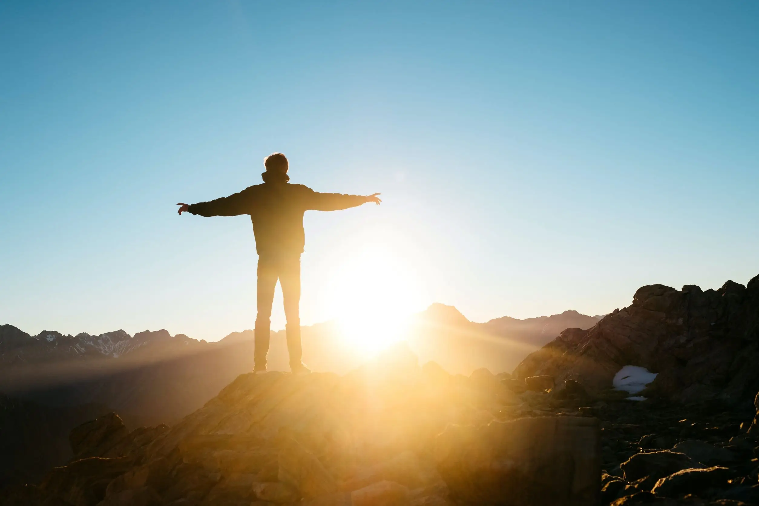 Gentleman on top of hill looking at sunset reflecting on his mental health recovery journey