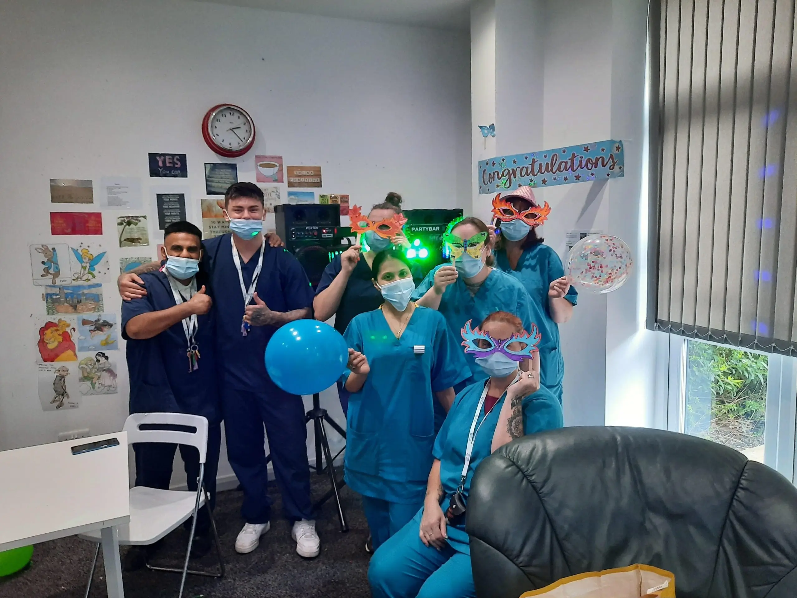team members posing with congratulations banners and balloons