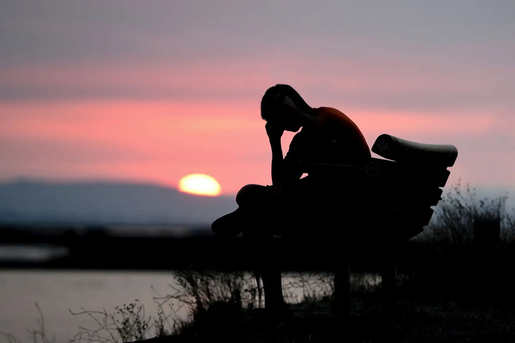 man on bench with head in hands