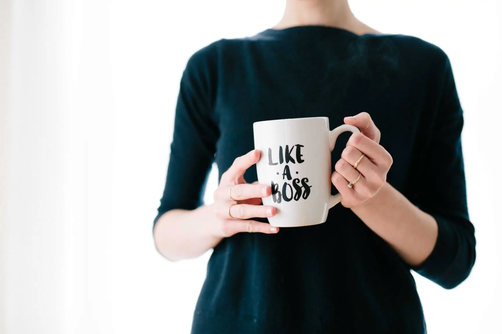 woman in green shirt holding mug that reads "like a boss"