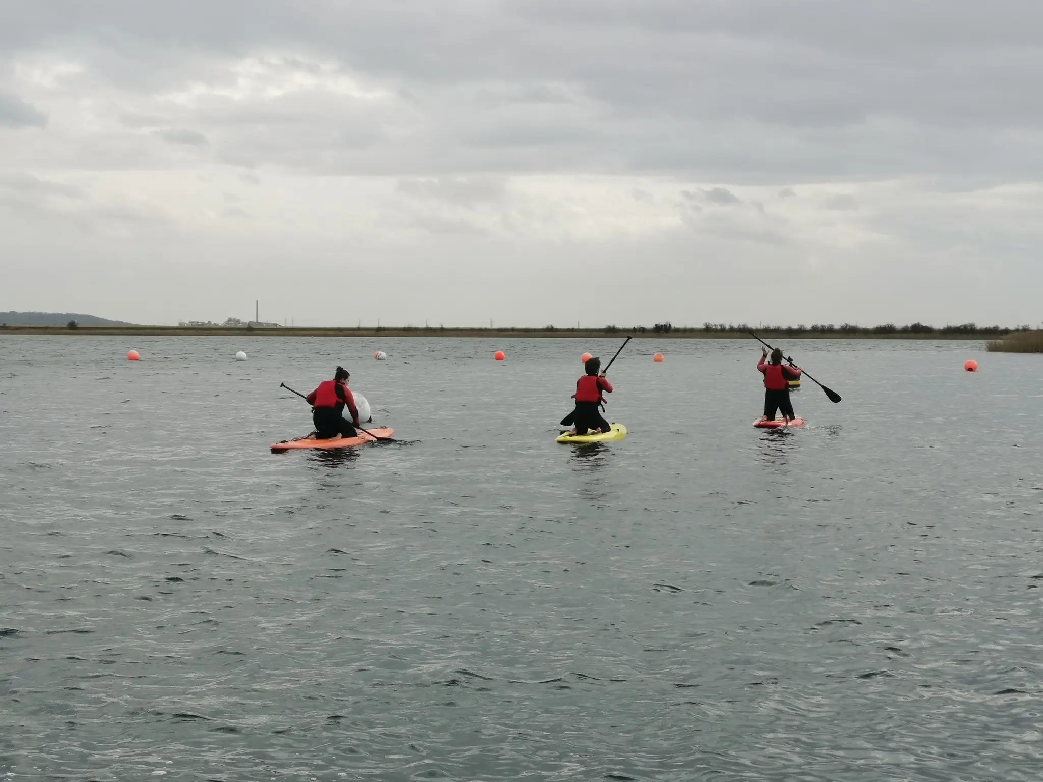 Three people on a lake paddle boarding