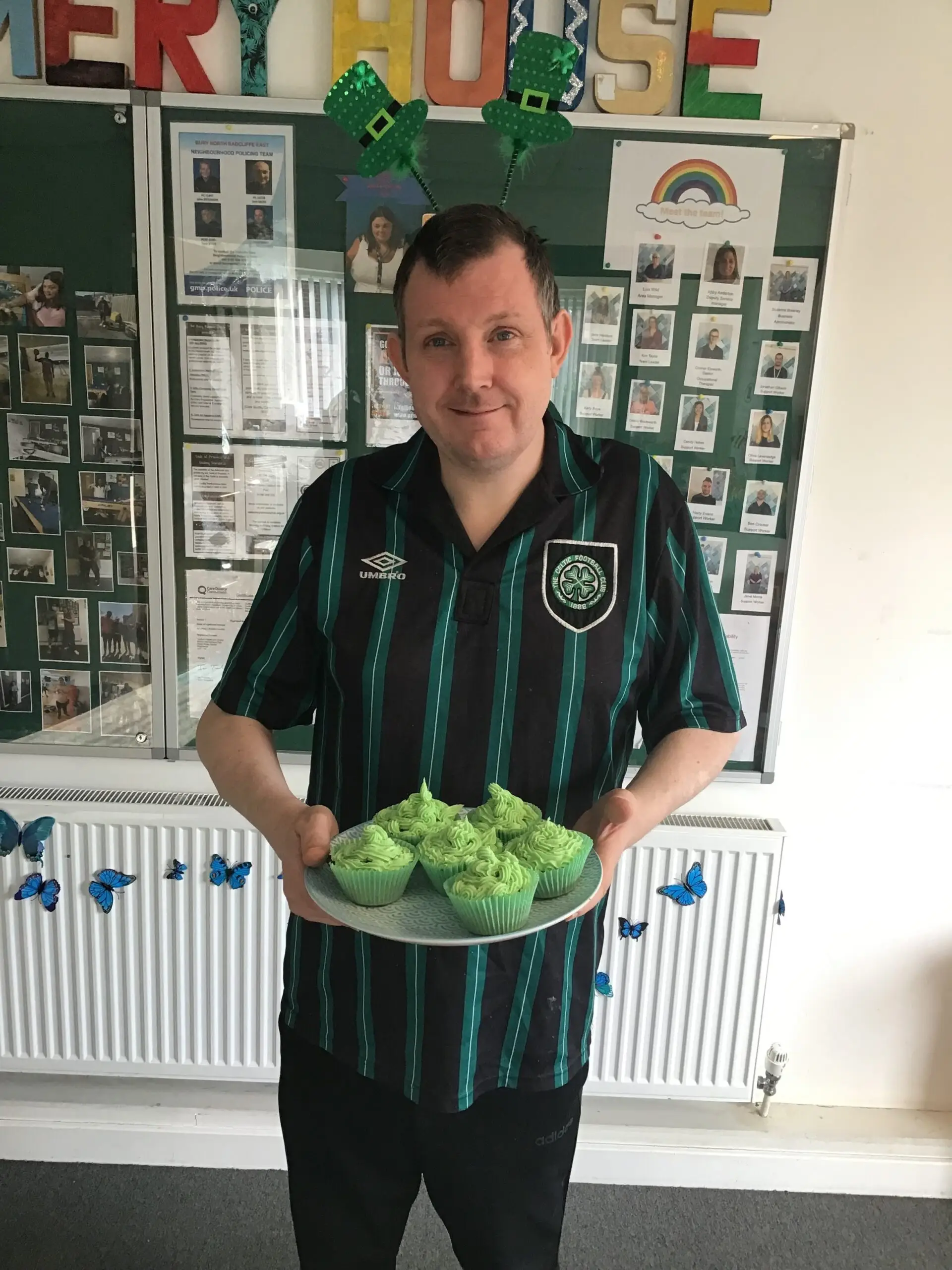 resident holding tray of cupcakes decorated with green icing