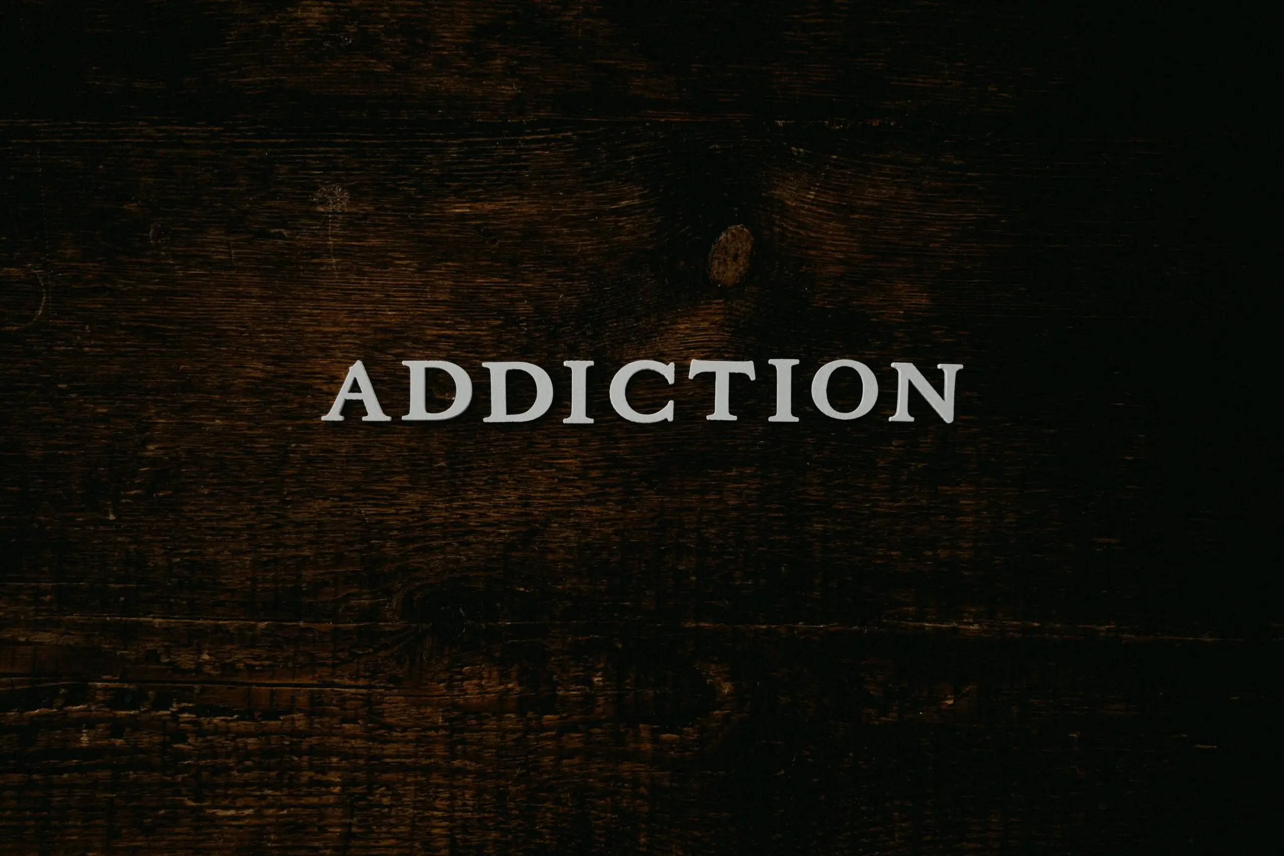 addiction spelled out in white letters on wooden background