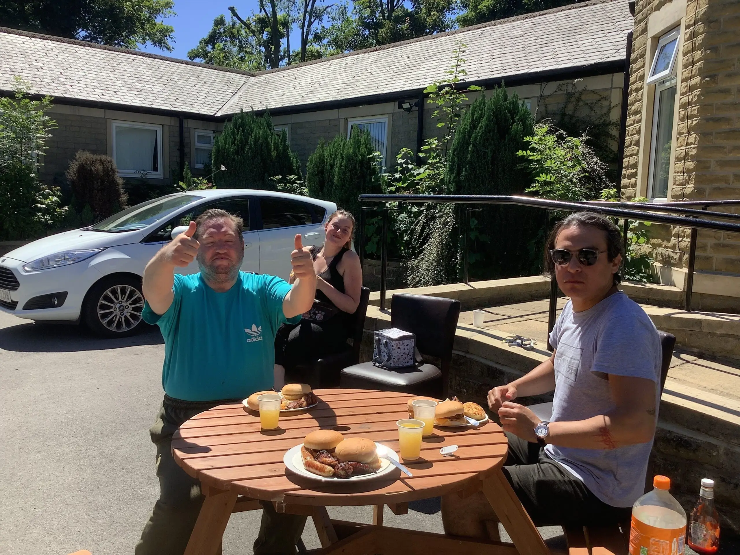 3 residents enjoying bbq sat on picnic bench