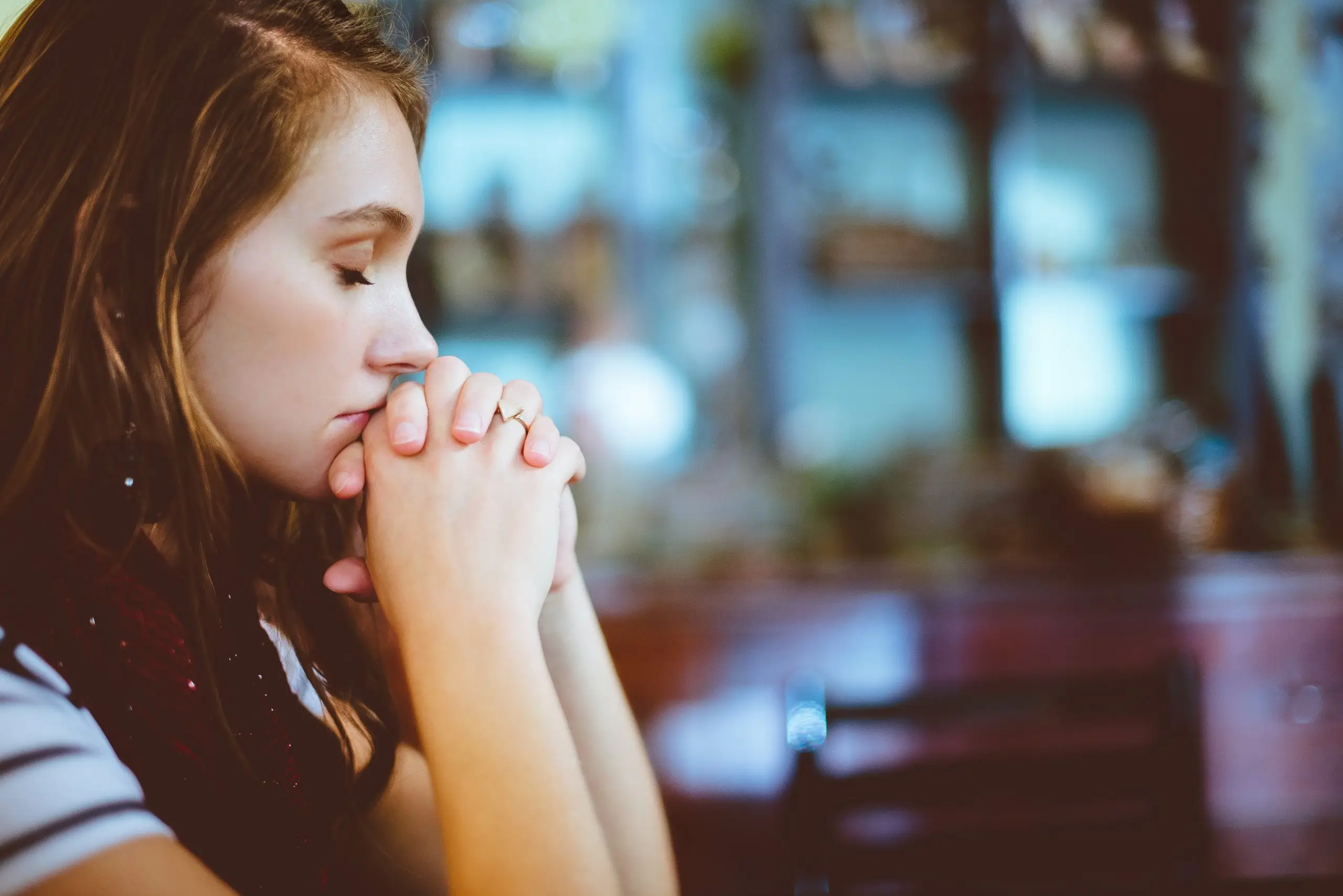 woman with eyes closed, and hands clasped in front of chin