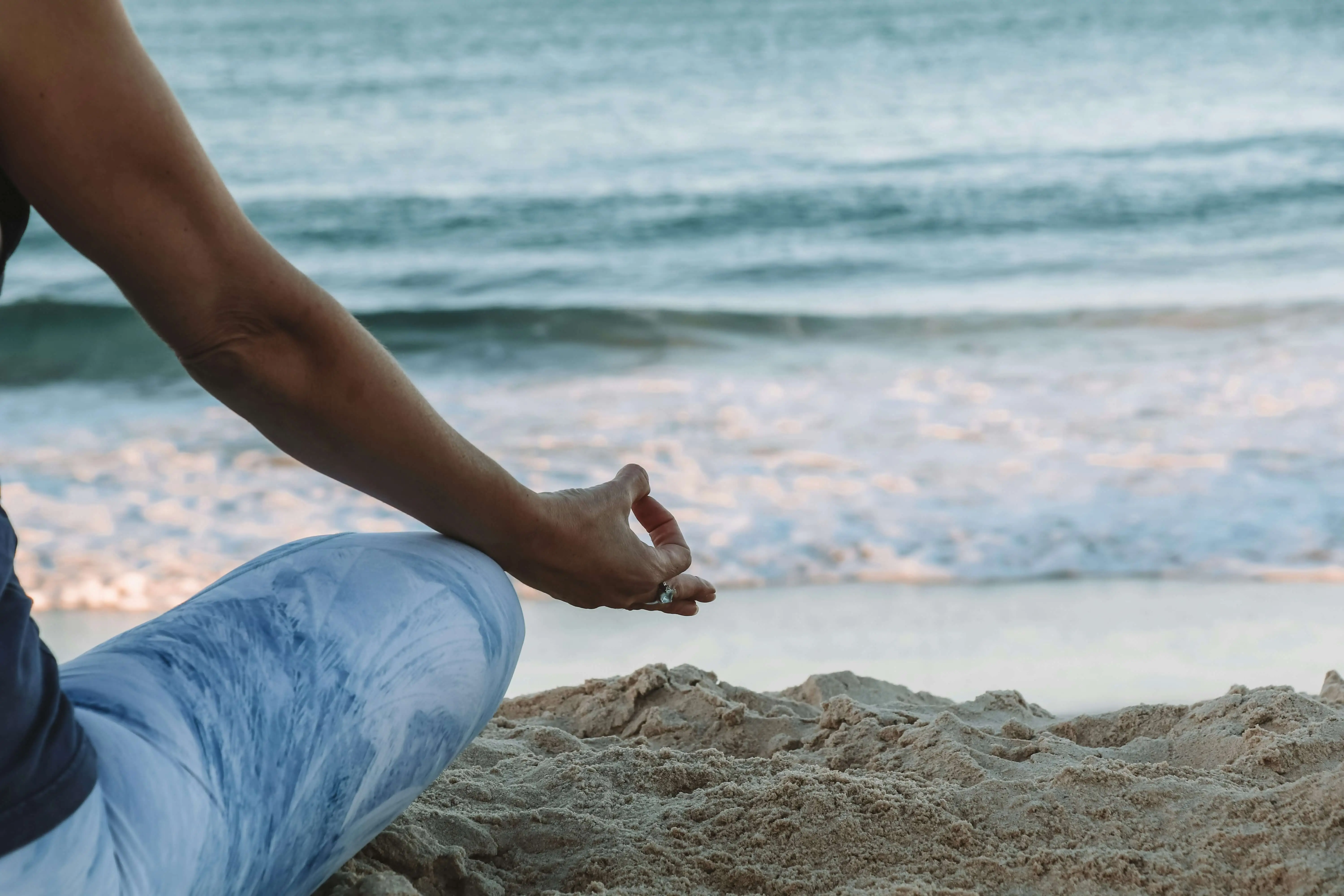 A person meditating on a beach representing mindfulness and inner peace.