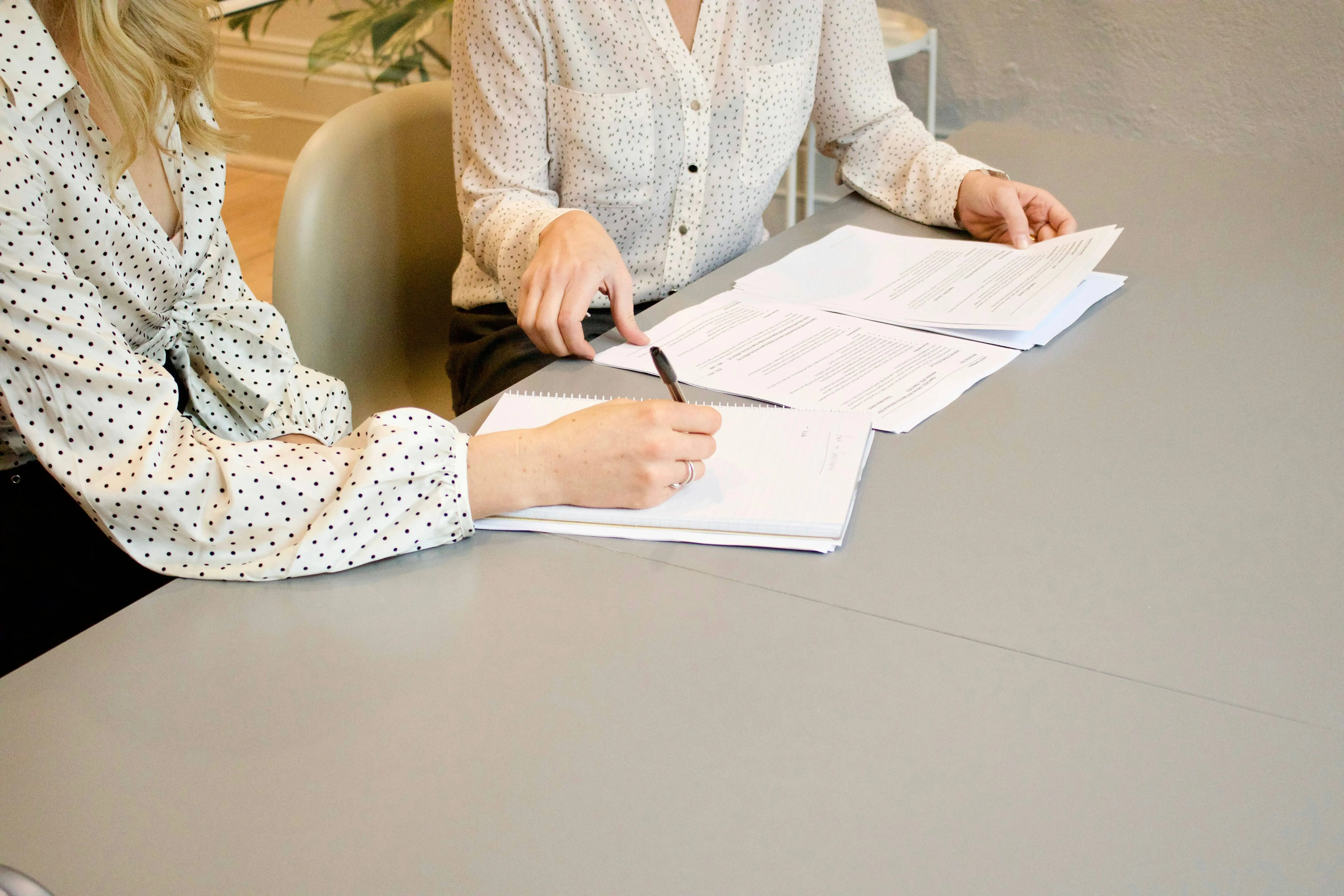 Two women comparing employment documents for a blog on supported living and pathways into work.