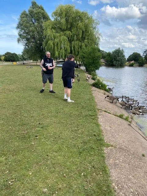 2 males feeding geese