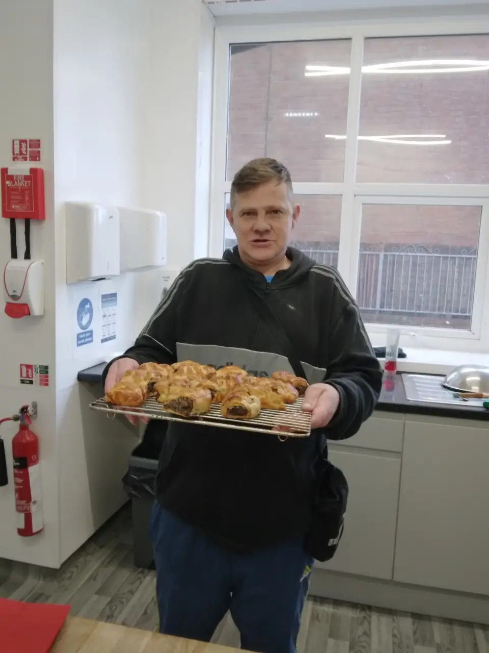 resident holding tray of homemade haggis sausage rolls