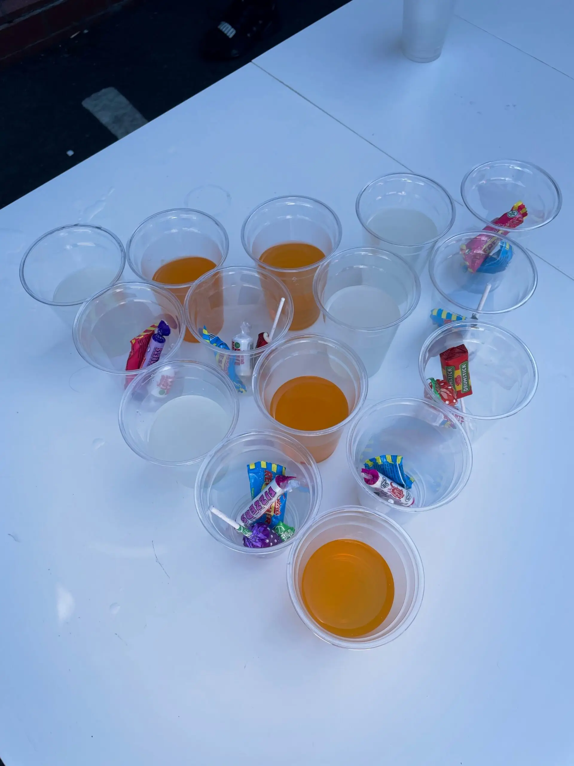 plastic cups in pyramid shape - half filled with juice, half filled with sweets