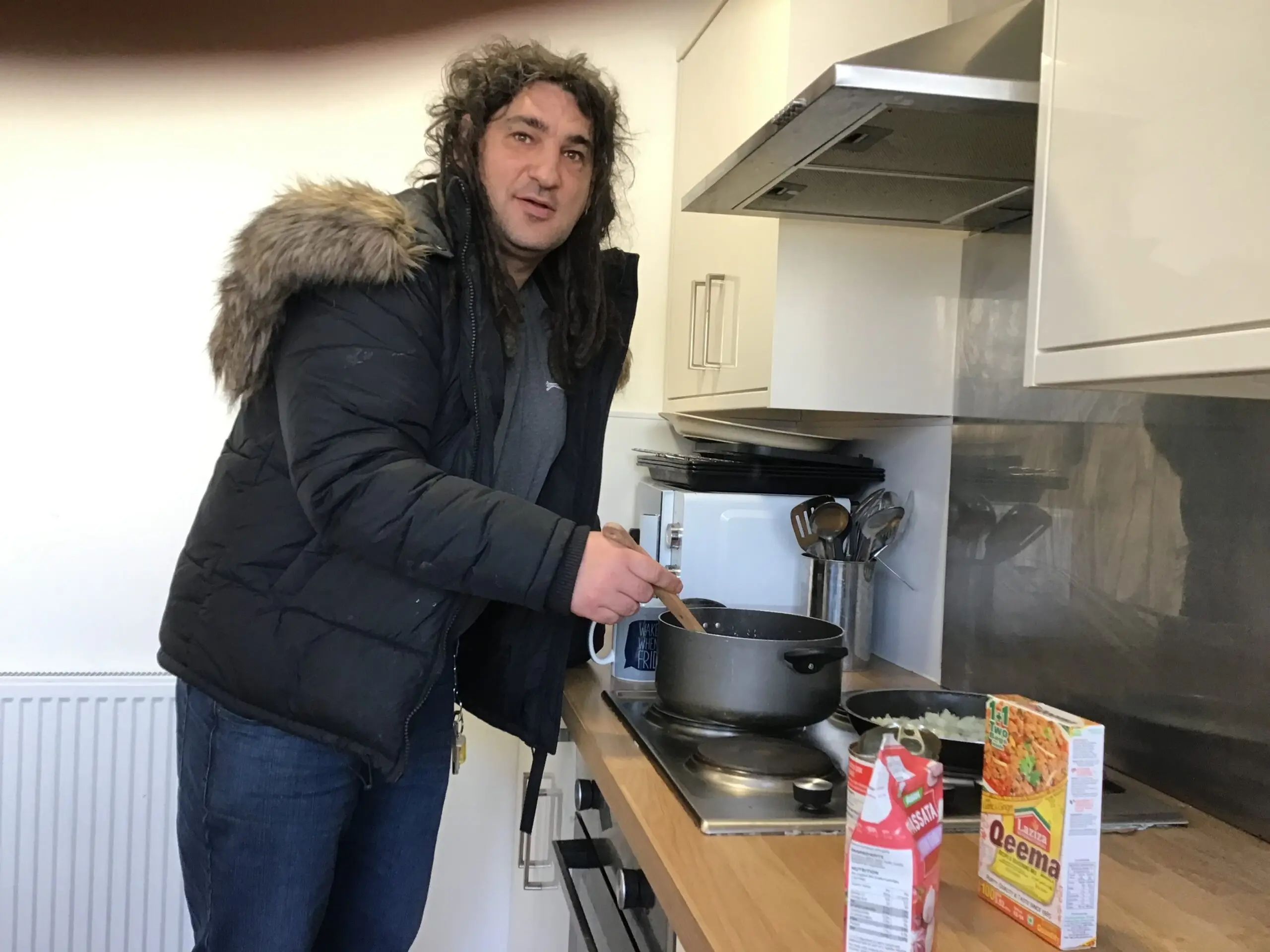 male resident stirring curry on pan