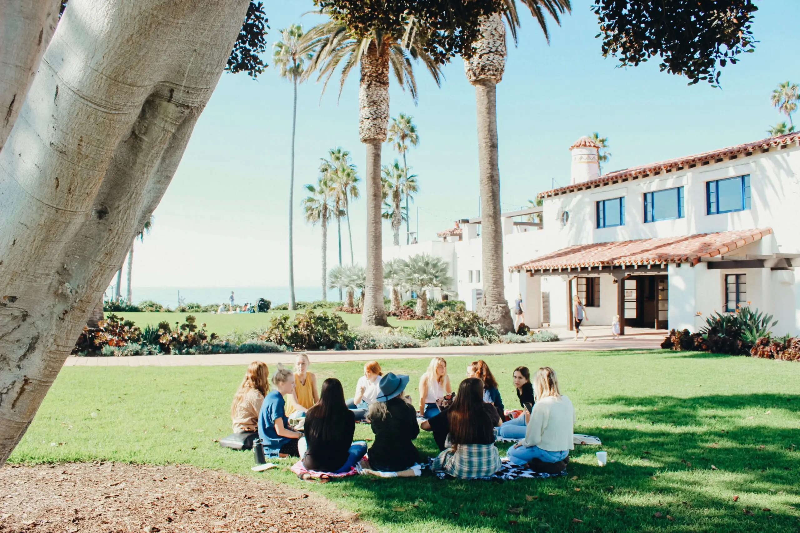 group of people sat in a circle on grass outdoors