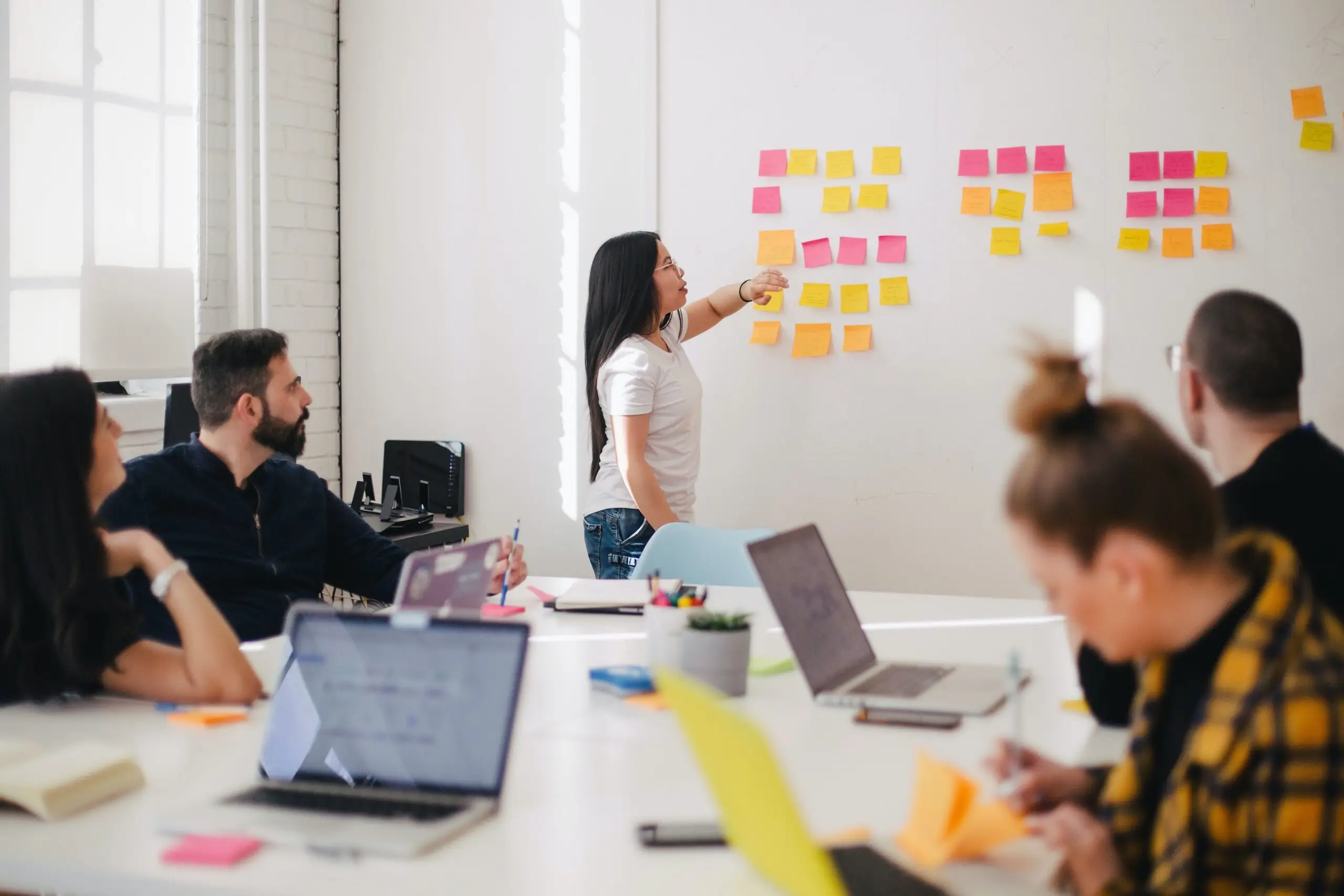 woman training colleagues with post-it note display