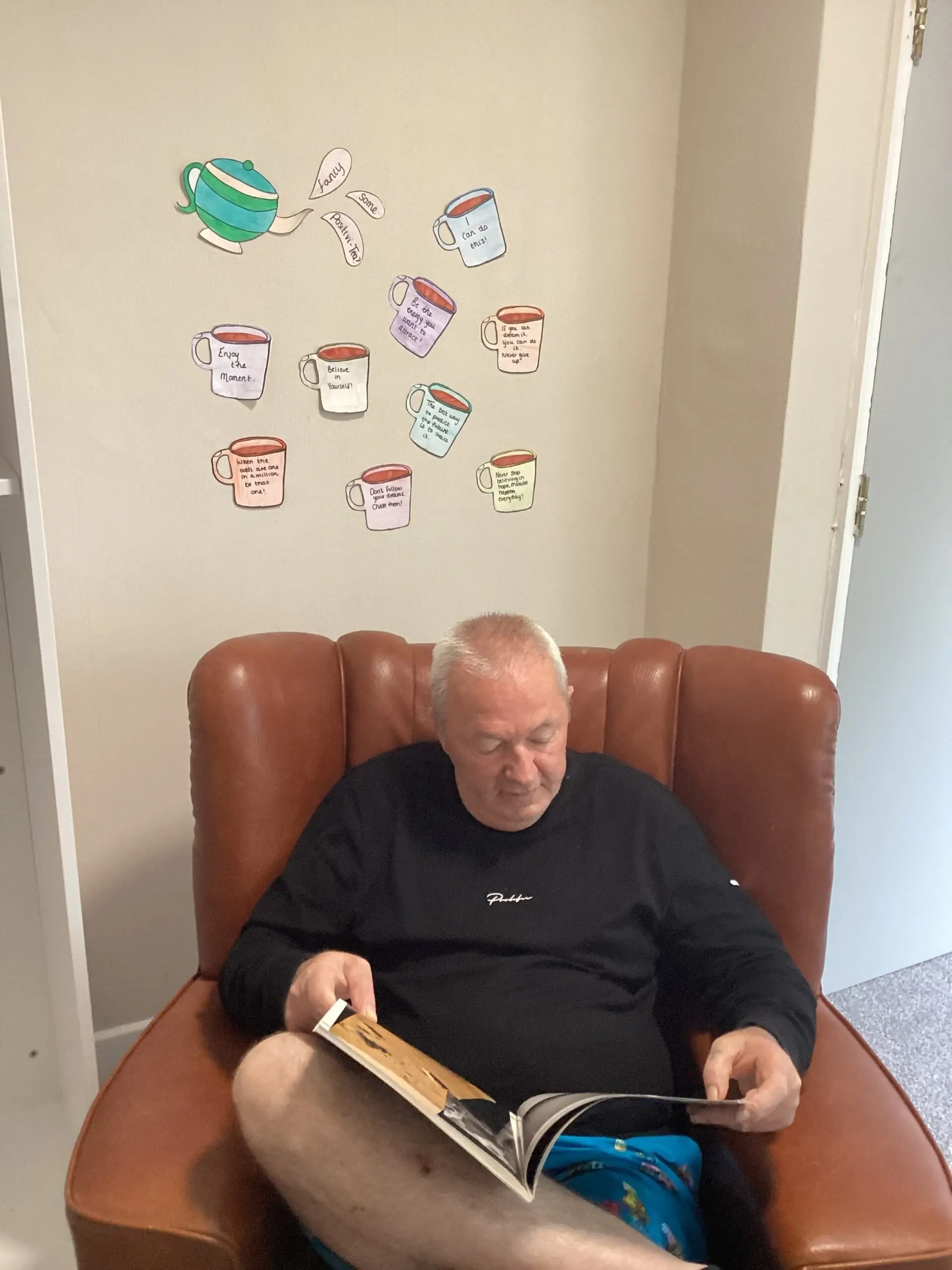 male resident reading book in red armchair