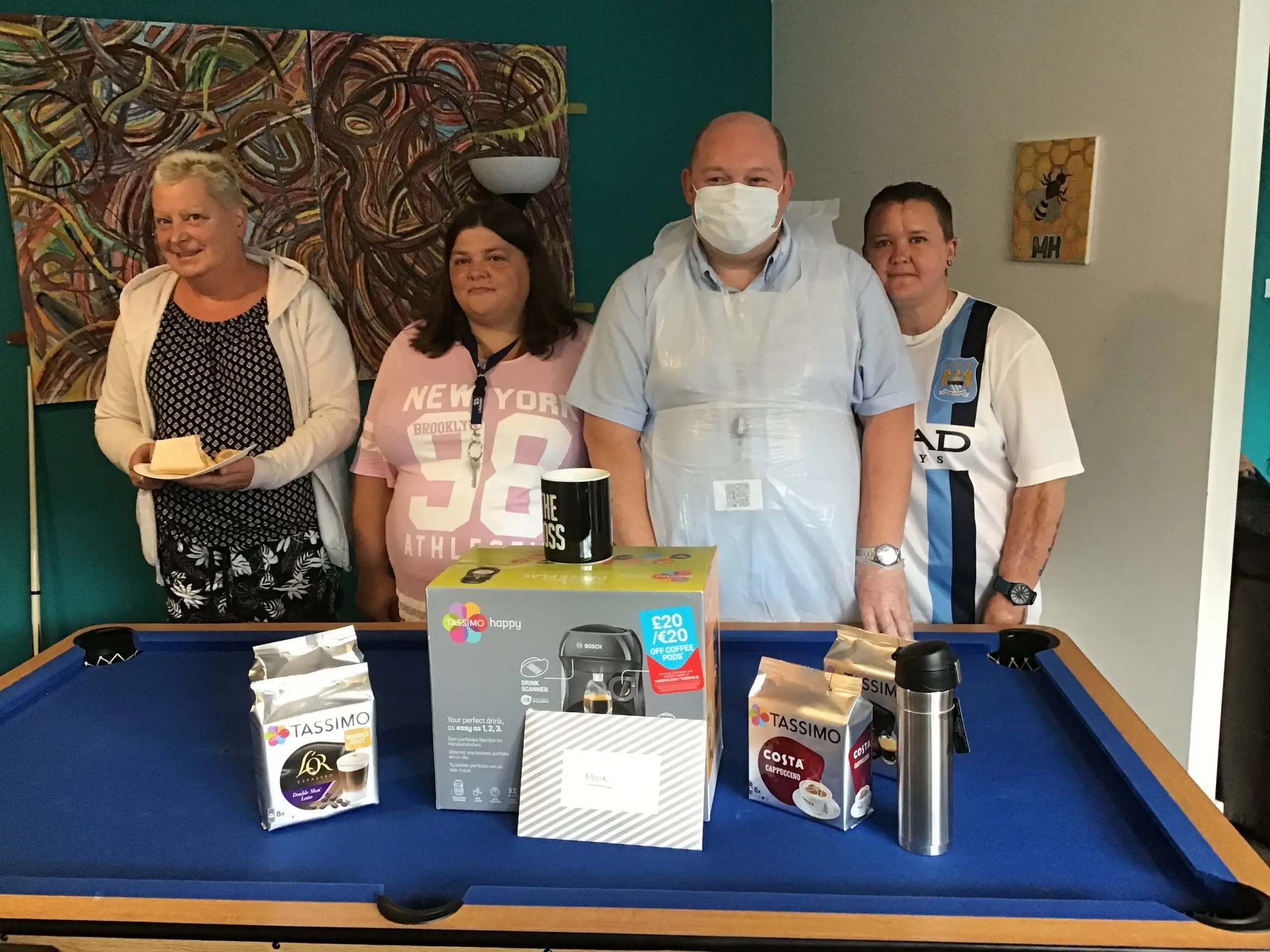 team member and residents posing with coffee machine